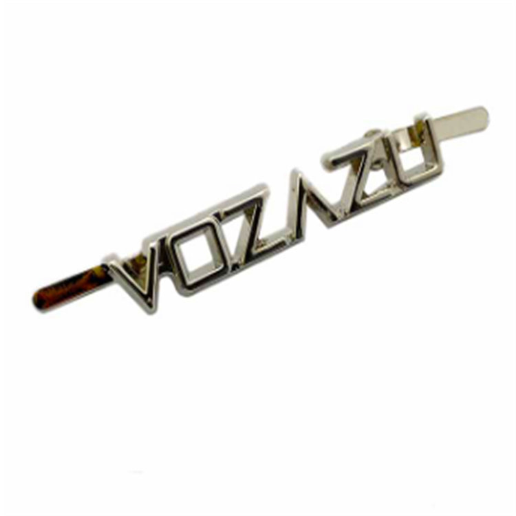 Złoty, spersonalizowany wypust z logo w kształcie litery na tylnej metalowej płytce torby